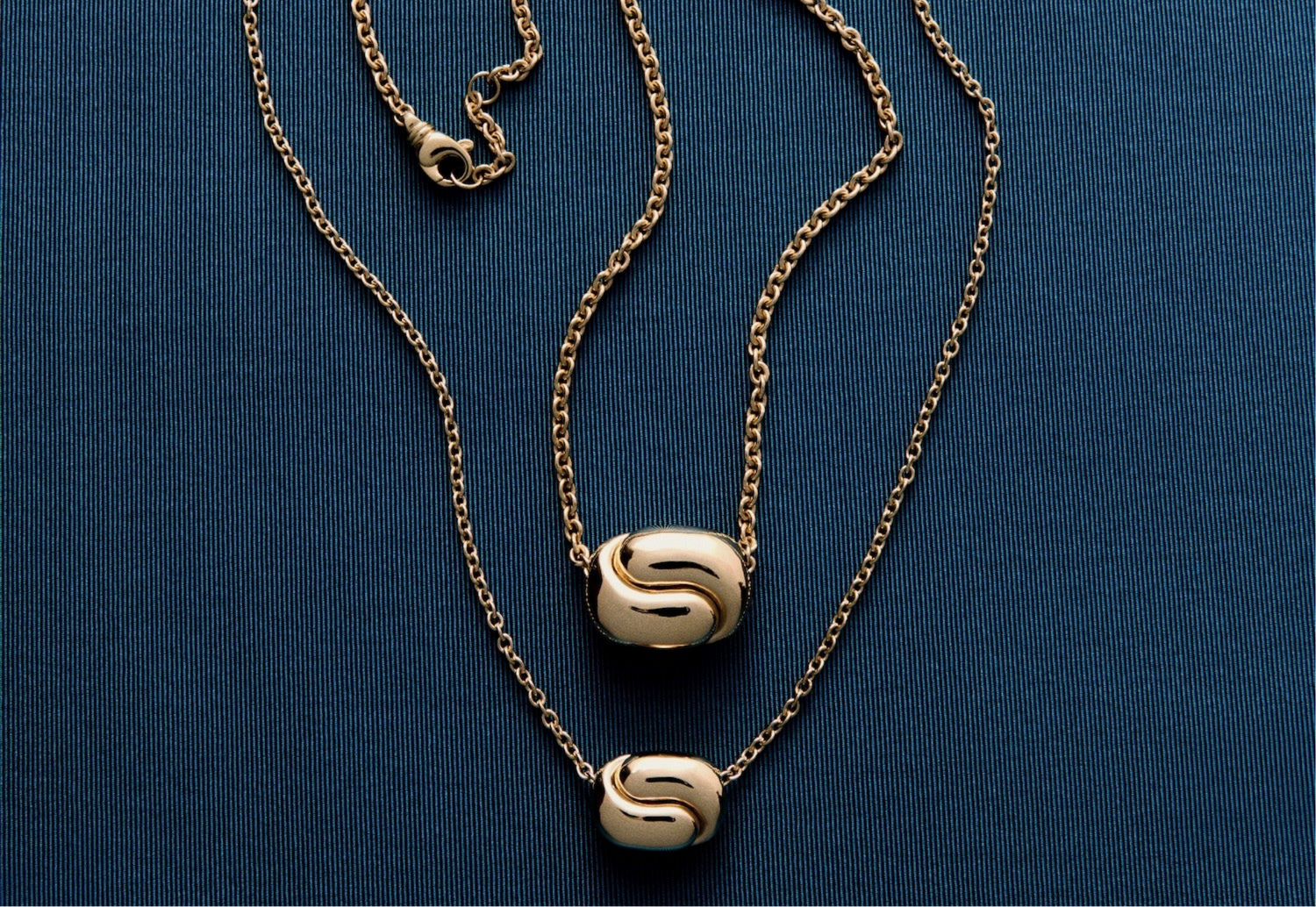 Gold necklace with a decorative clasp on a blue background pamela zamore