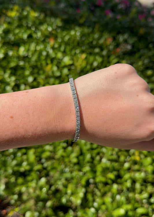 Hand wearing a bracelet with a green leafy background